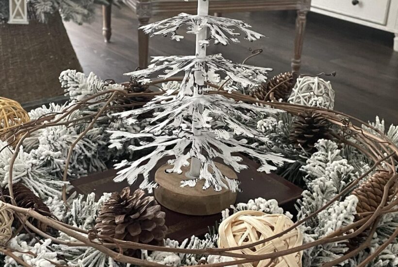 A white metal Christmas tree surrounded by an evergreen and grapevine wreath.