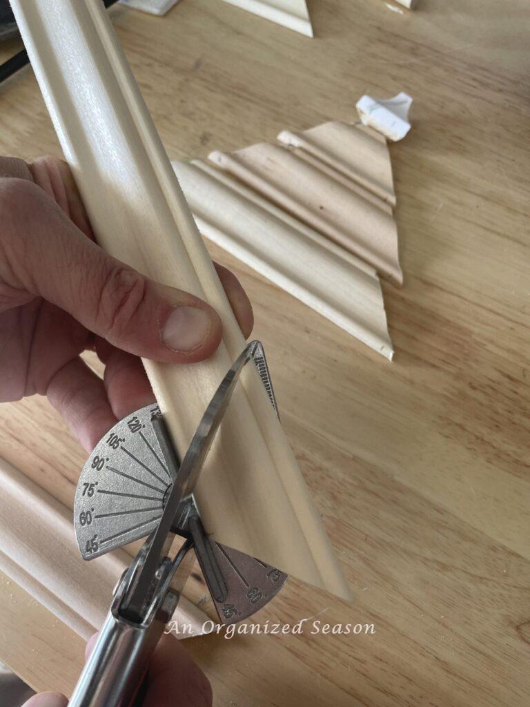 Step three to make a wooden Christmas tree is to cut the wood trim at a 45 degree angle with a miter shear.