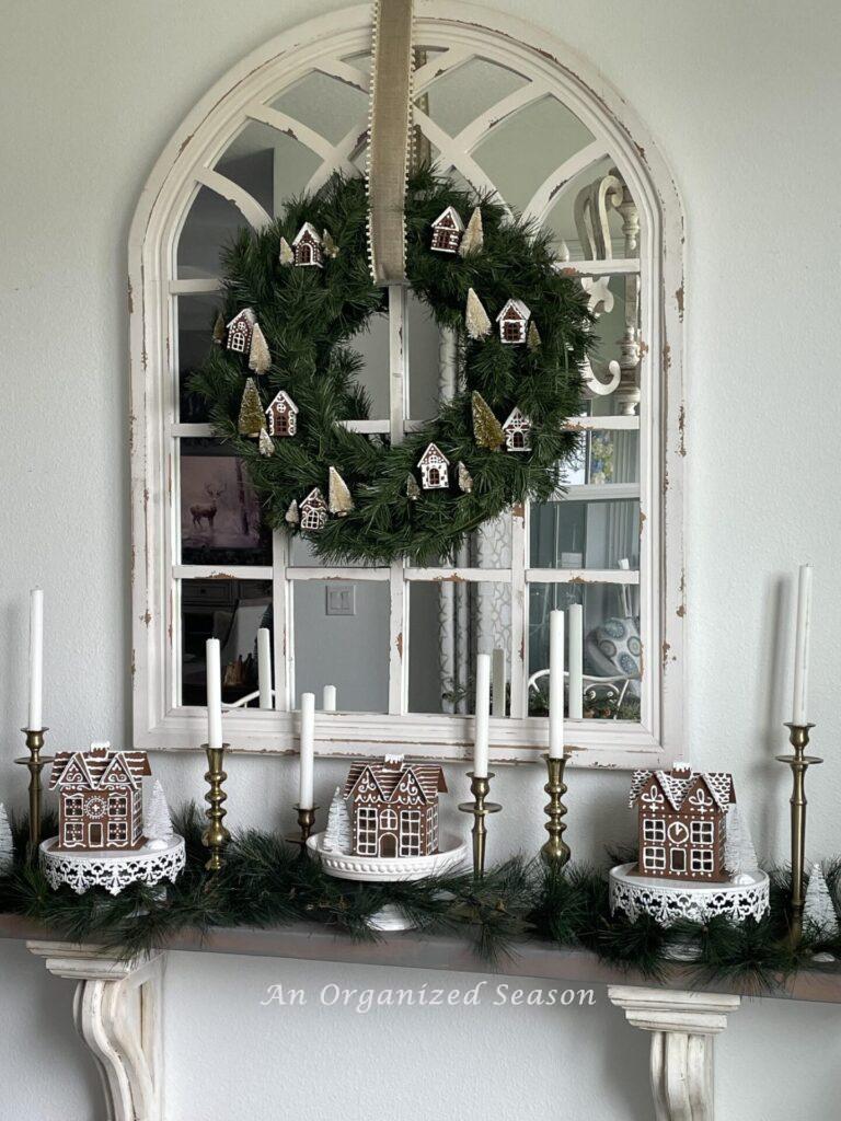 DIY gingerbread houses displayed on a shelf with a gingerbread house wreath hanging above it! 