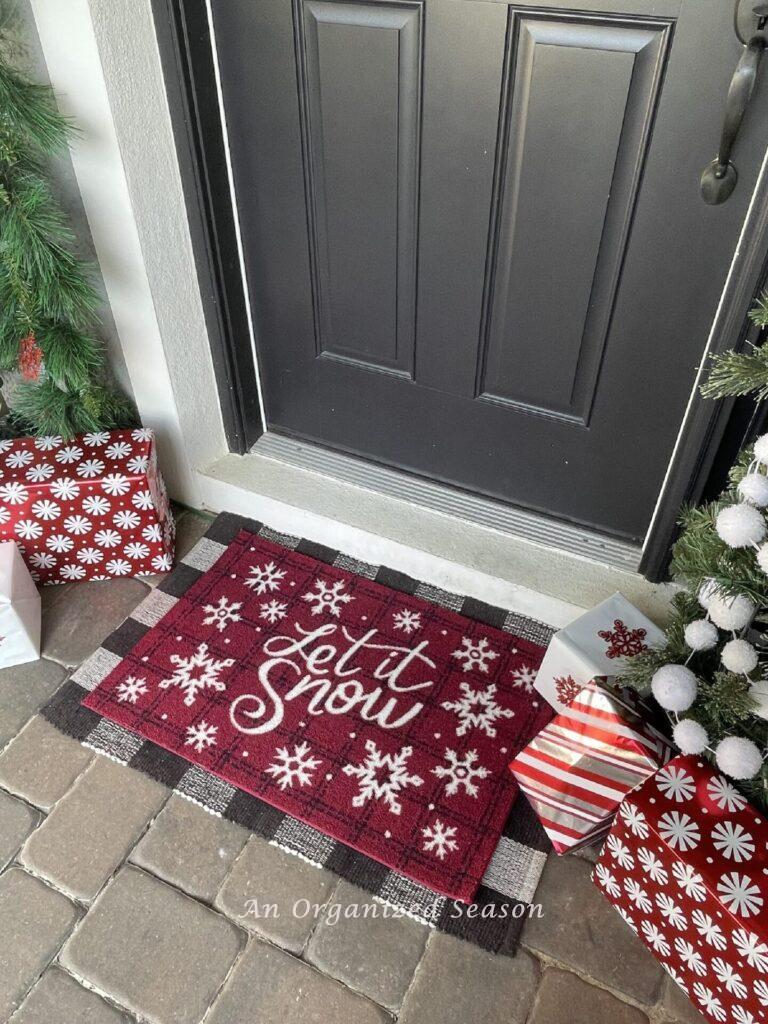 Layered rugs in front of a door make festive Christmas porch decor.