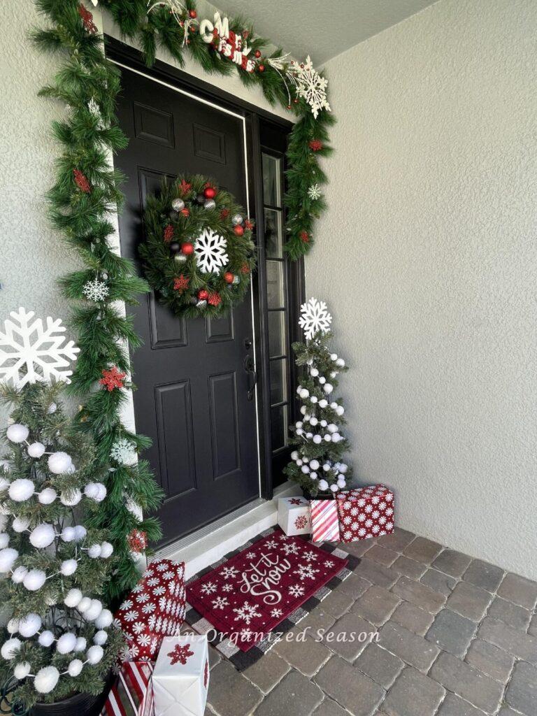 A front porch decorated for Christmas with red and white items. 