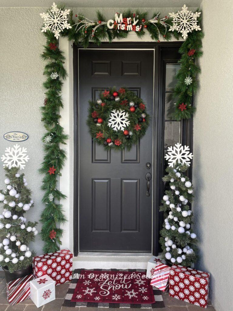A front door decorated for Christmas with snow flakes and snow balls. 