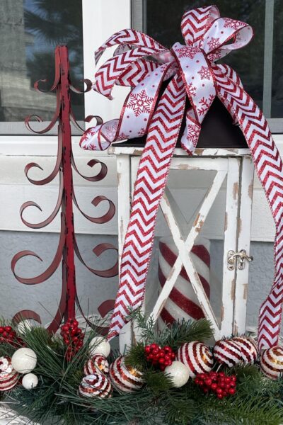 A red metal tree and white lantern decorated with red and white ribbon.