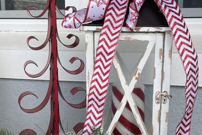 A red metal tree and white lantern decorated with red and white ribbon.