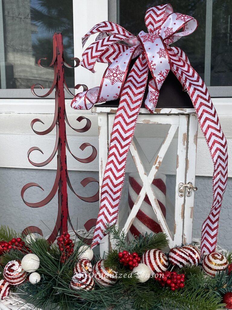 Metal tree, white lantern, and an evergreen spray make perfect Christmas porch decor. 