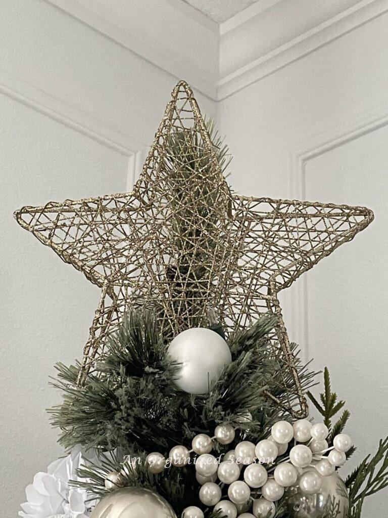 A gold star on top a Christmas tree. 