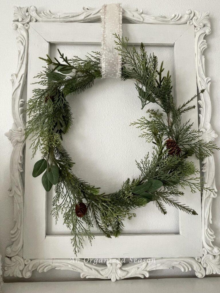 An evergreen wreath on a white antique frame. 