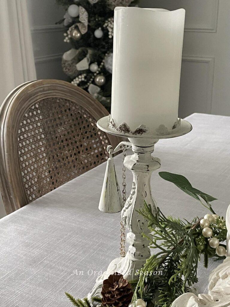 White candlestick with white pillar candle and snuffer is neutral Christmas decor.