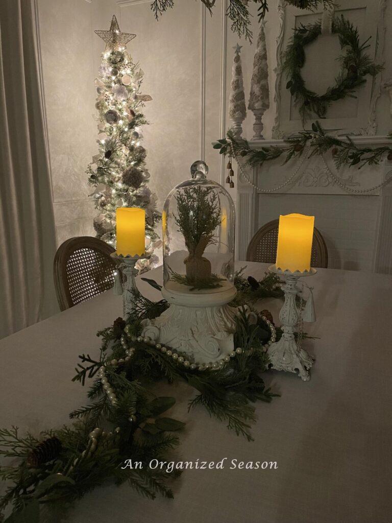 Candles on a dining table and tree in the corner are decorated for a Christmas home tour.