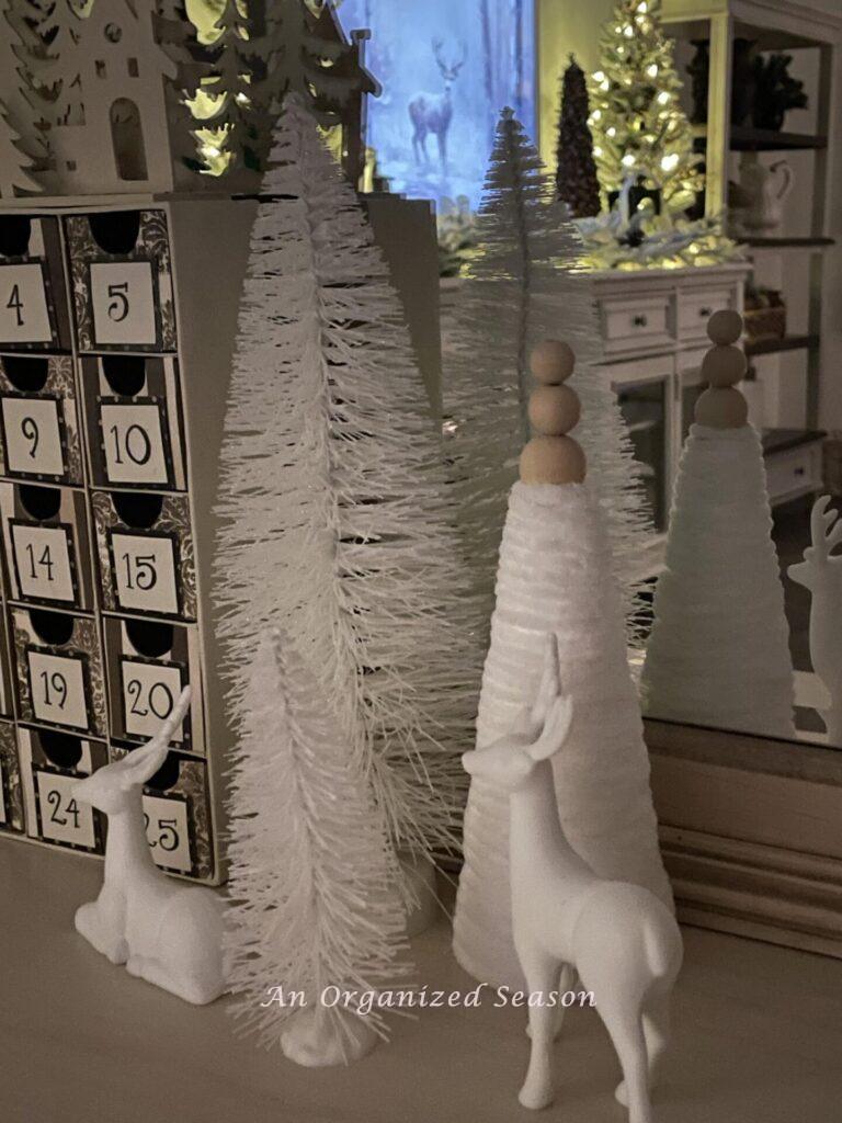 Bottle brush trees and deer next to an Advent calendar. 