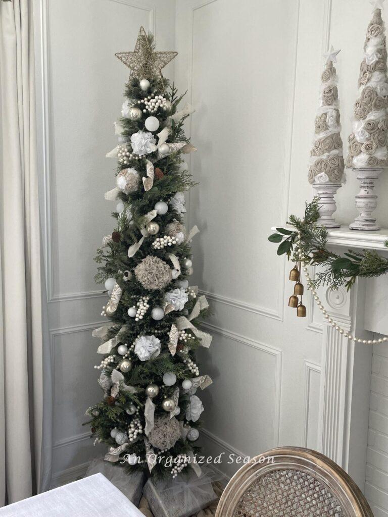 A skinny Christmas tree with neutral decor.