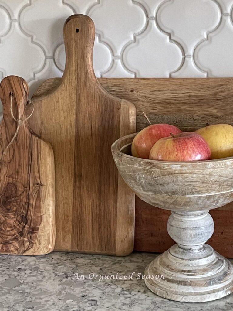 A kitchen counter with wood cutting boards and a bowl of apples. 