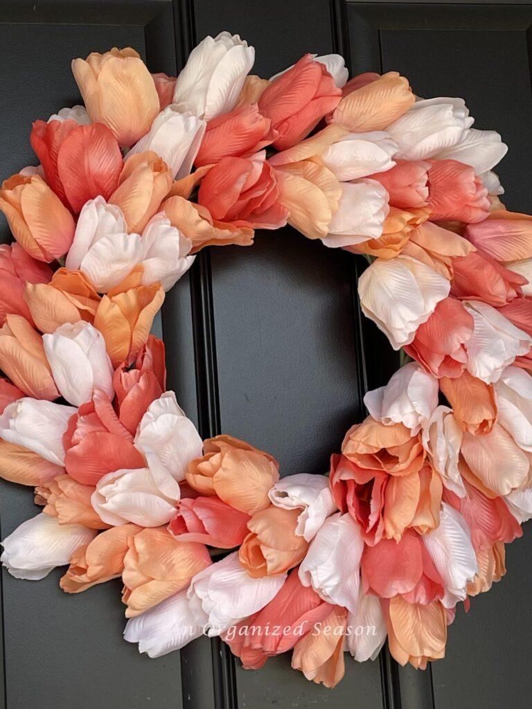 A wreath made with three colors of tulips: white, orange, and peach. 
