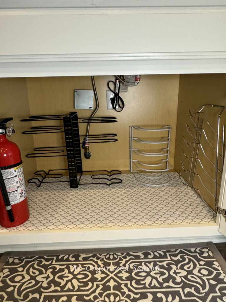 A kitchen cabinet with liner and organizers for cookware. 