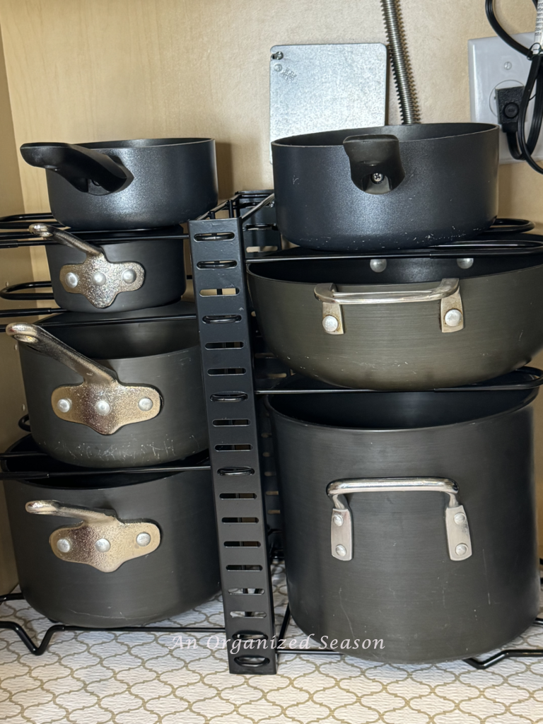 Organize pots and pans on a vertical rack in a cabinet. 