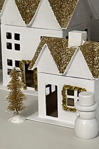 White house with gold glitter roof, snowman, and gold bottle brush tree