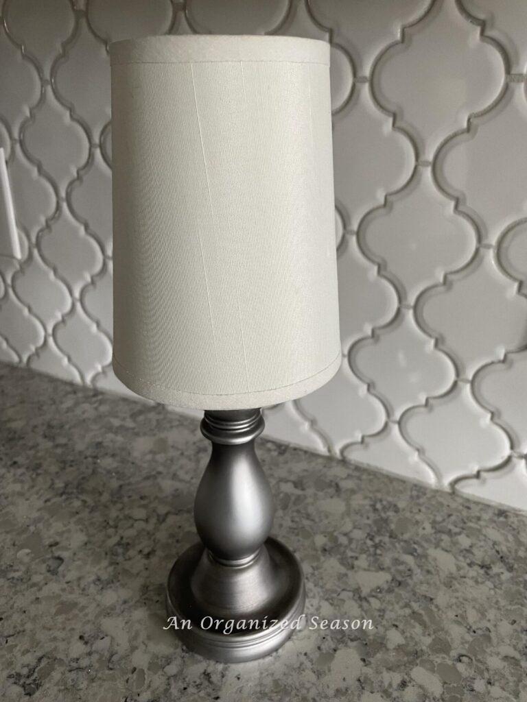 Step three to make a DIY lamp is to place the lampshade on top of the candlestick.