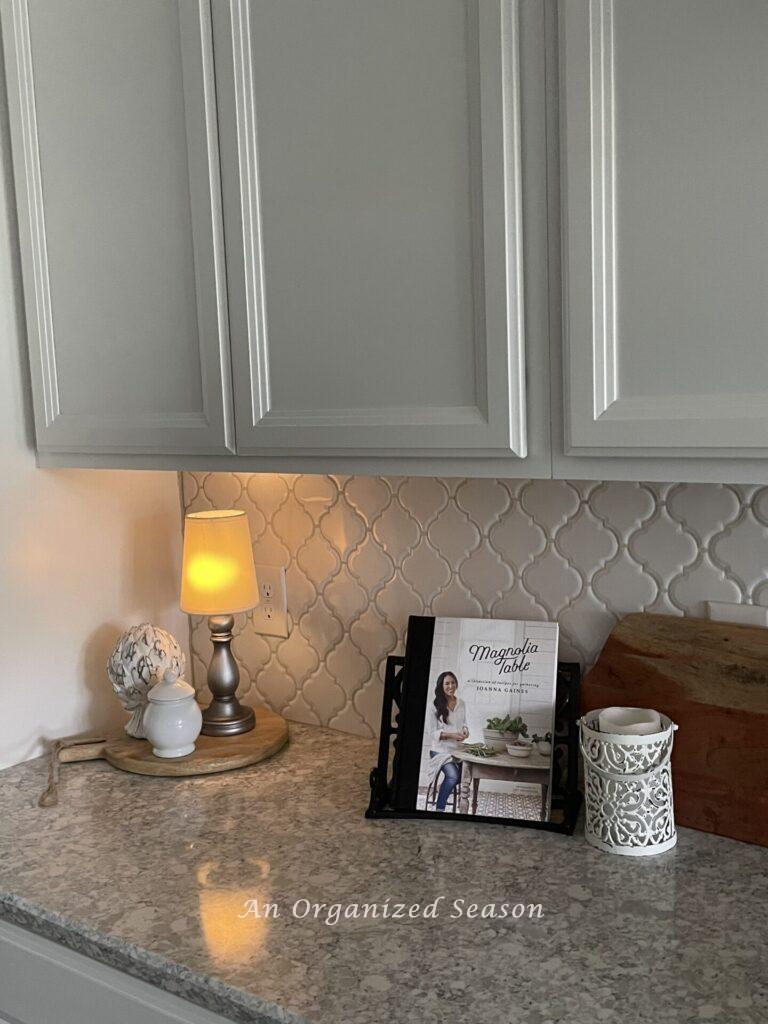 A small lamp lights the corner of a kitchen countertop.