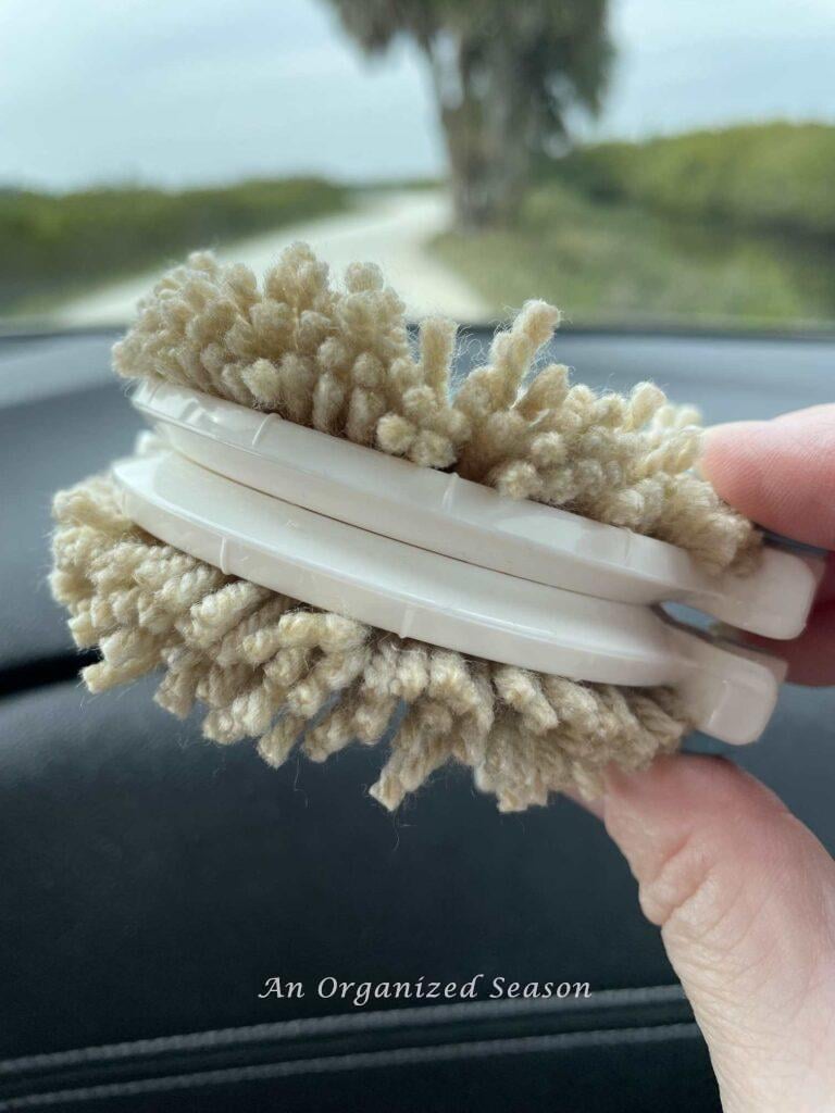 Cut yarn on a pom pom maker.