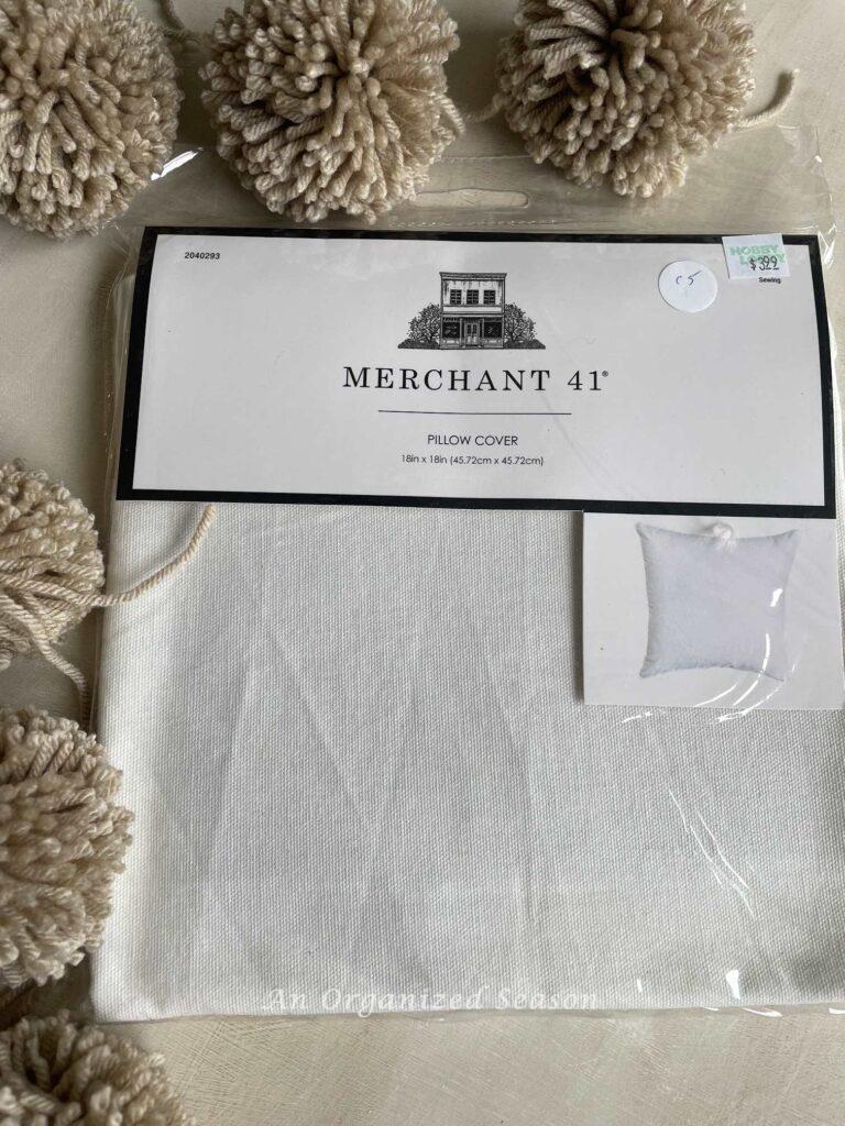 Make a DIY pillow by adding pom poms to a pillow cover bought from Hobby Lobby.