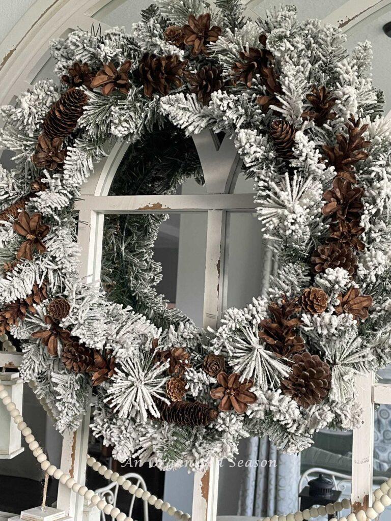 Make Winter decor by adding pinecones to a flocked wreath. 