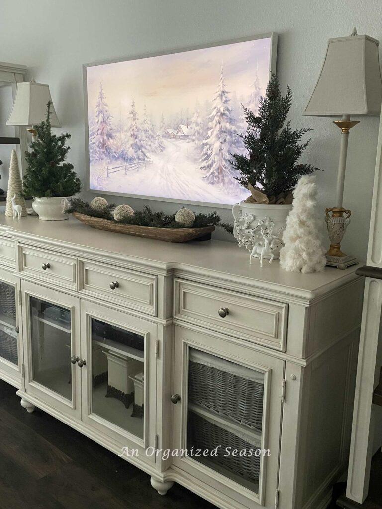 A TV console table with Winter decor and a Winter scene on the frame TV. 