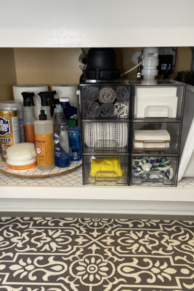 Under kitchen sink cabinet organized with clear drawers and a lazy Susan.