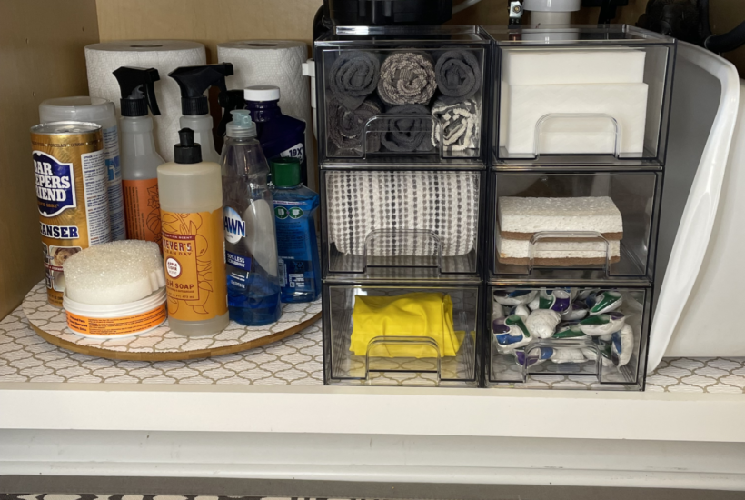 Under kitchen sink cabinet organized with clear drawers and a lazy Susan.