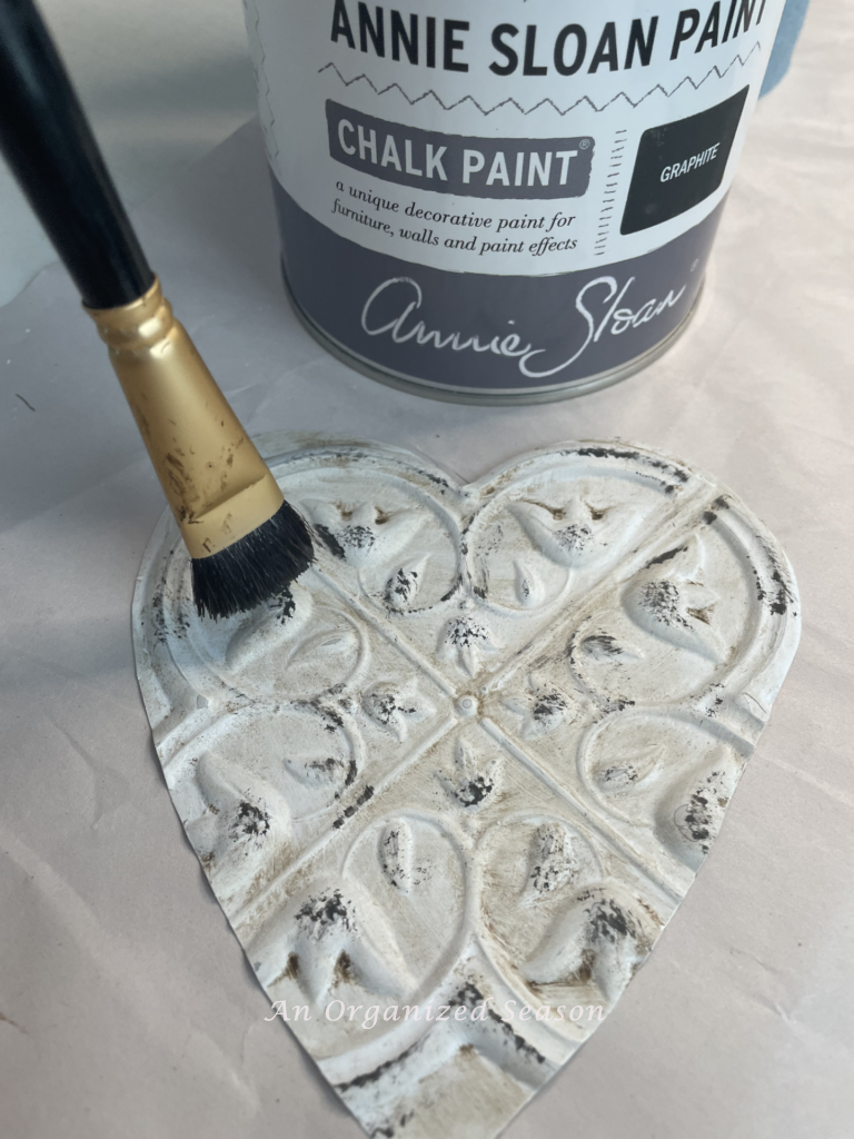 A faux tin heart being distressed with paint. 