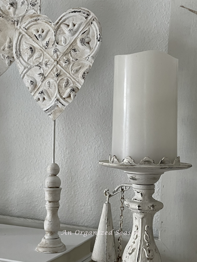 A standing heart next to a vintage candleholder. 