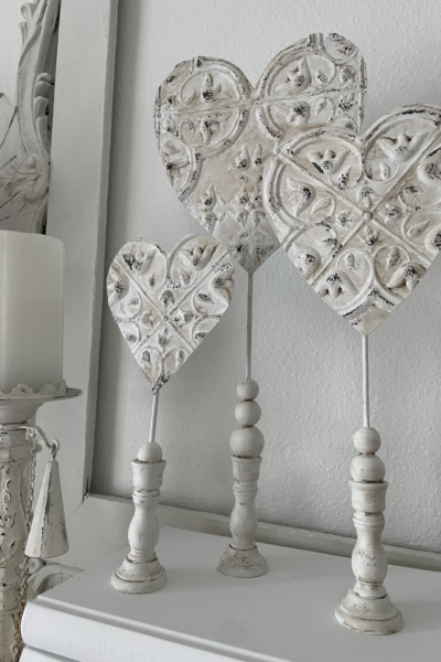 Three faux tin hearts on wood stands.