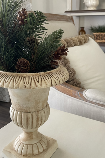 Evergreen branches and pinecones displayed in an urn.