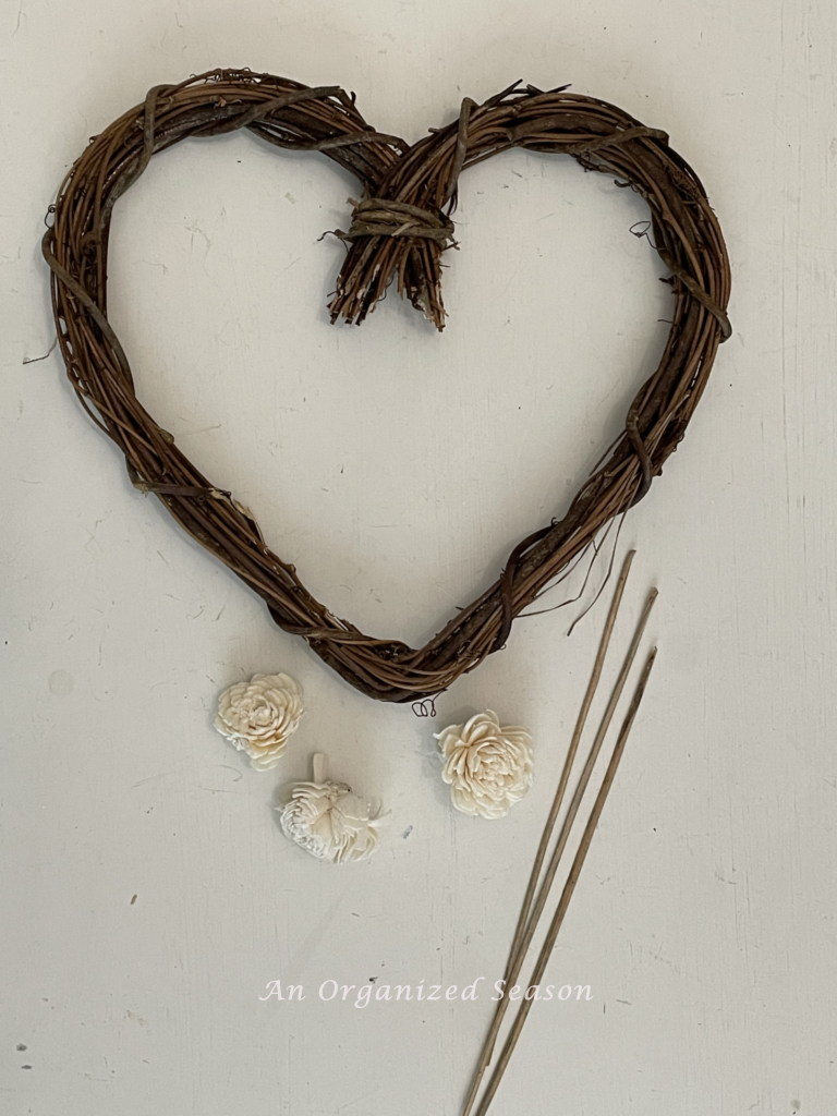 Step two to make a grapevine heart wreath DIY is to remove the wood flowers from their stems.