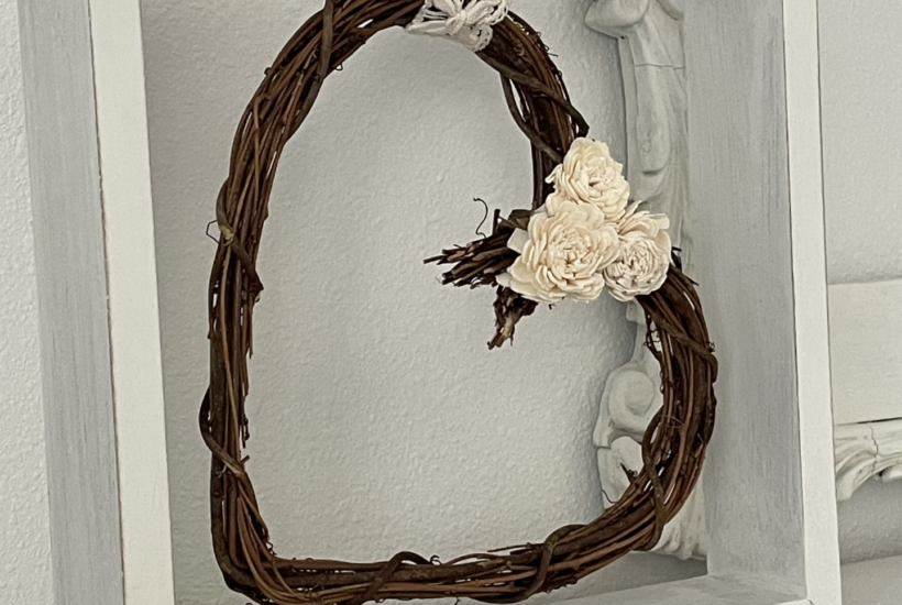 grapevine heart wreath hanging in square wood frame.