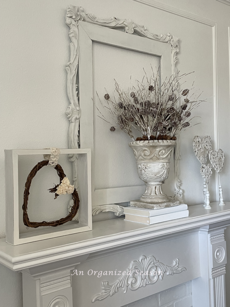 Heart wreath hanging inside a frame on a fireplace mantel. 