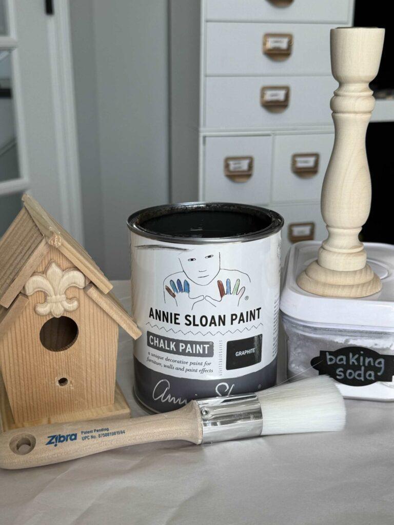 Wood birdhouse, candlestick, paint, baking soda, and paintbrush. 