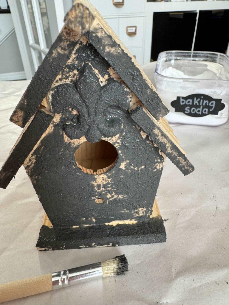 Wood birdhouse with black textured paint. 
