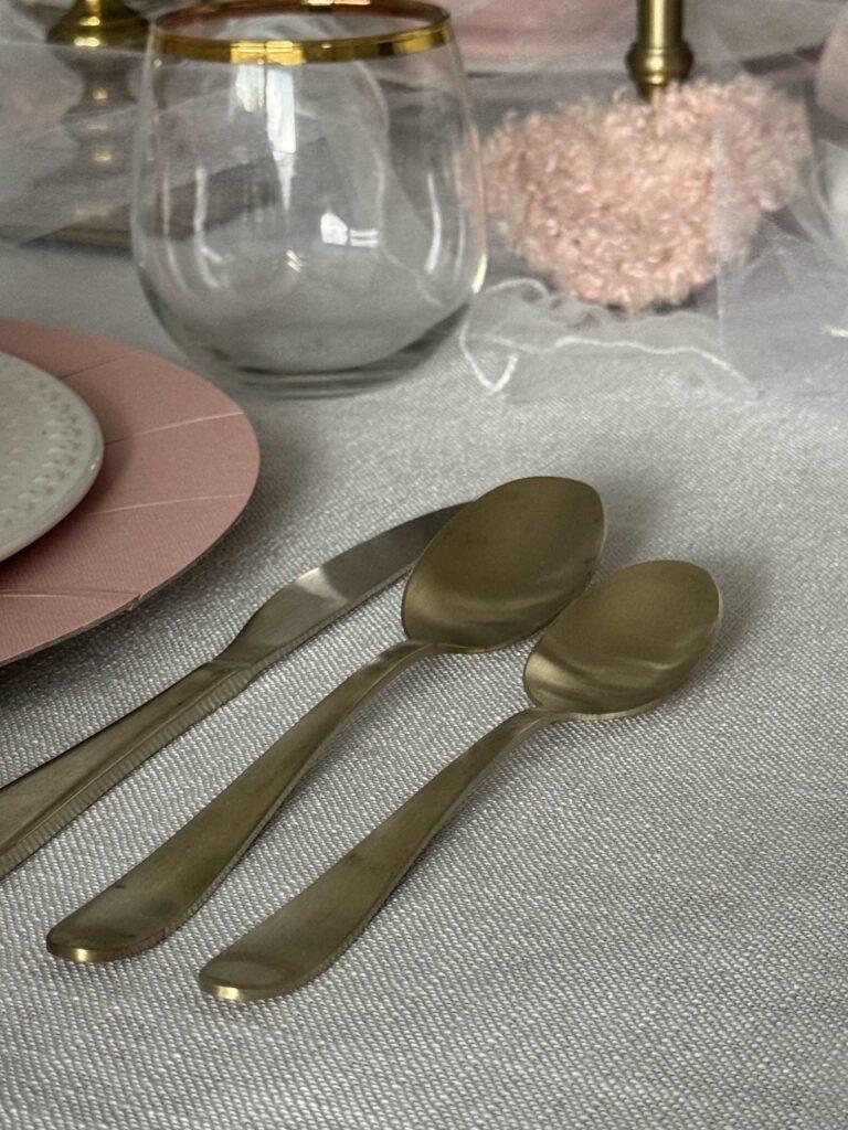Gold eating utensils and a gold-rimmed cup make pretty Valentine's table decor. 