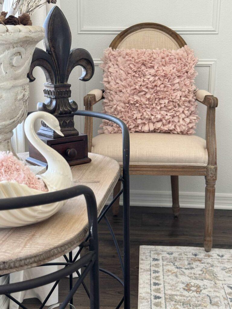 A pink pillow sitting on a chair. 