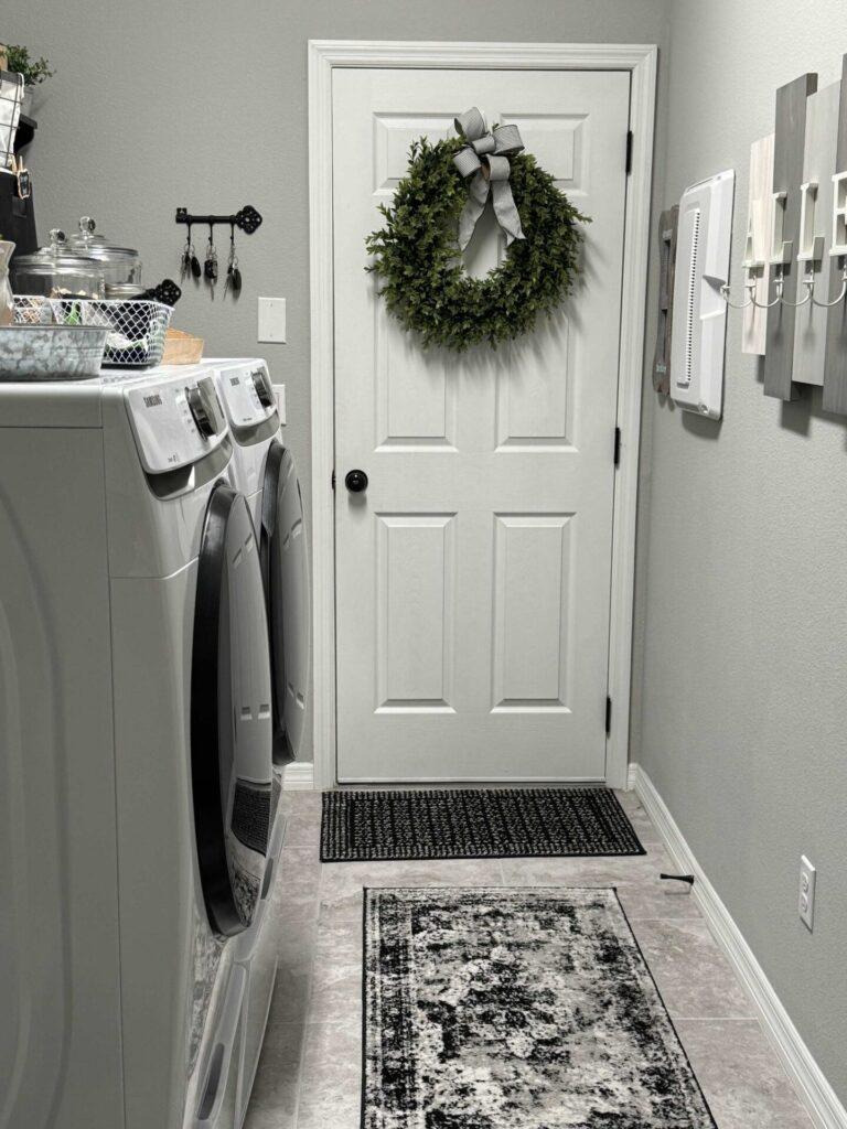 A laundry room door with a green wreath hanging on it. 