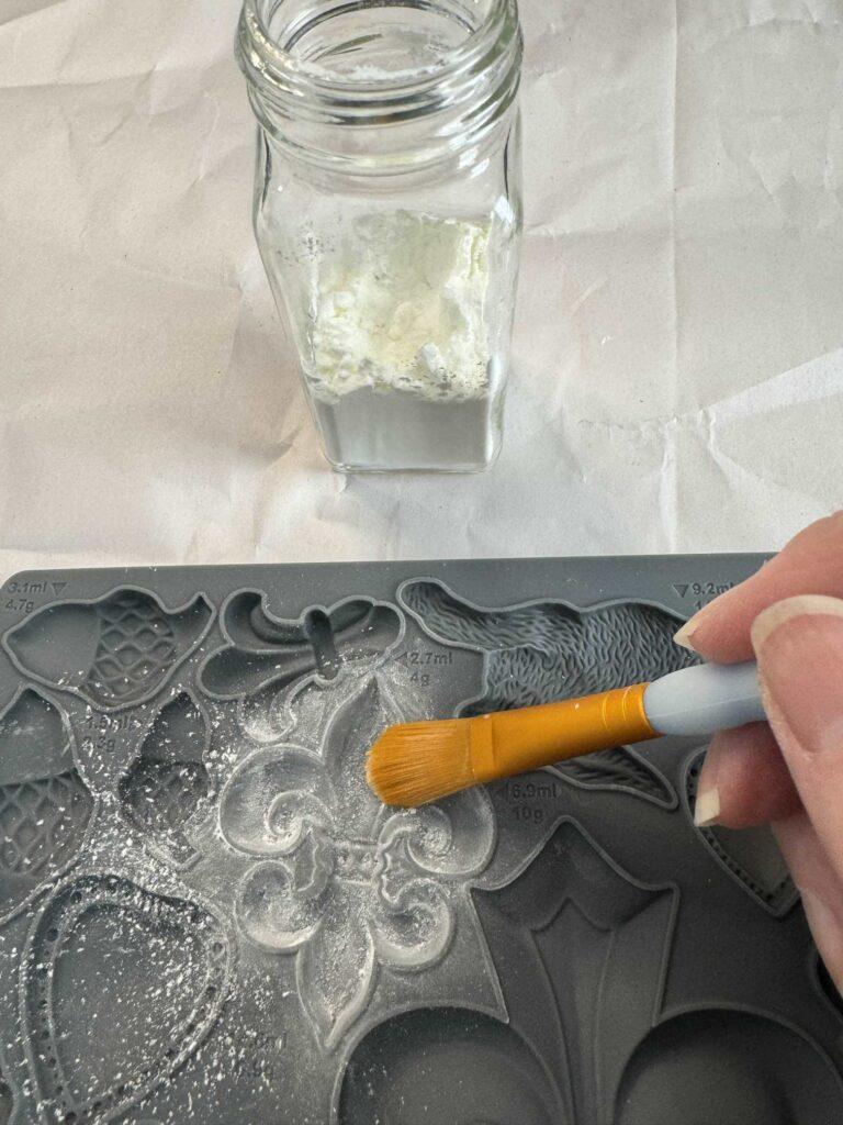 Someone brushing corn starch on a silicone mold. 