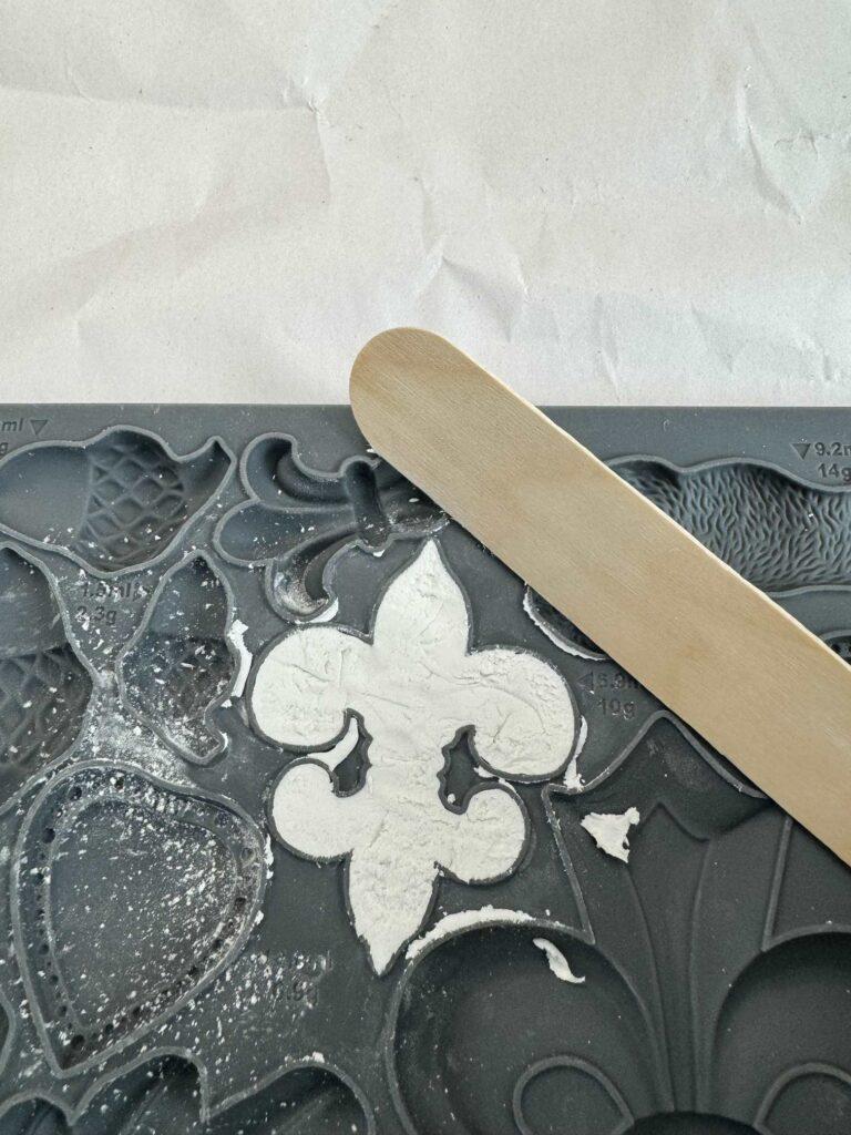 Clay pressed into a fleur de lis silcoine mold. 