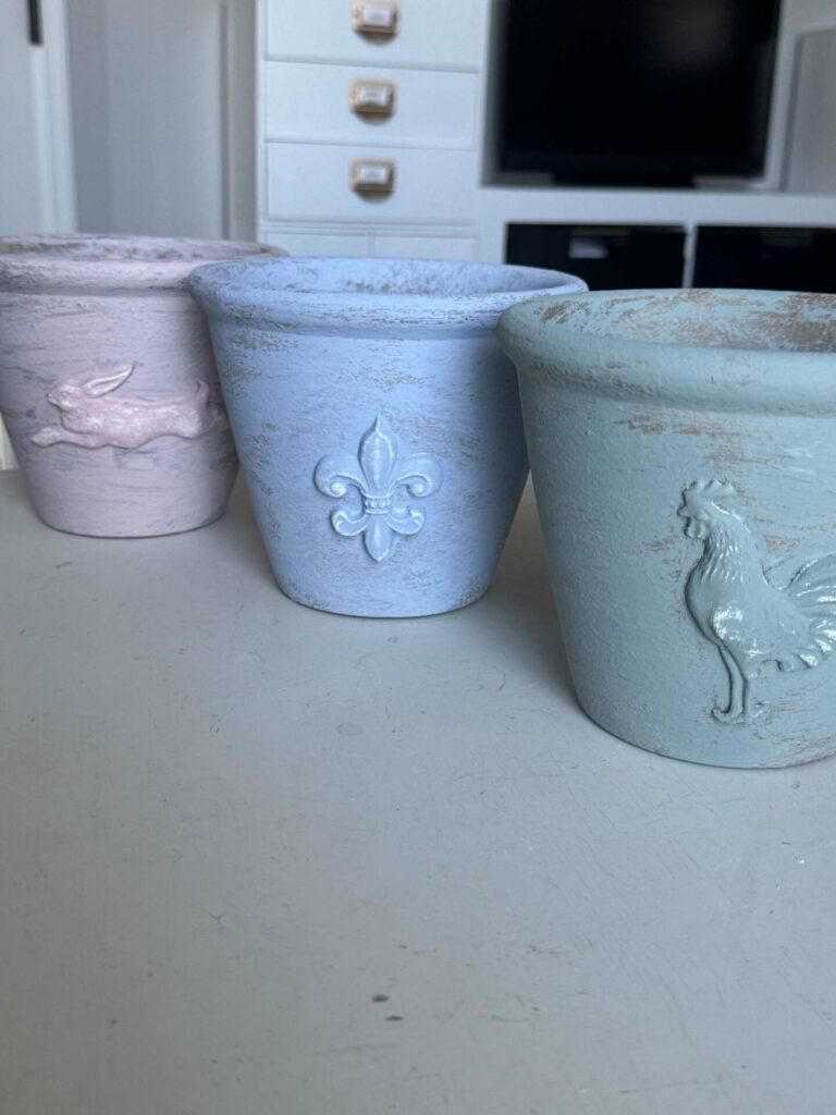 Three DIY flower pots painted pink, green, and blue.