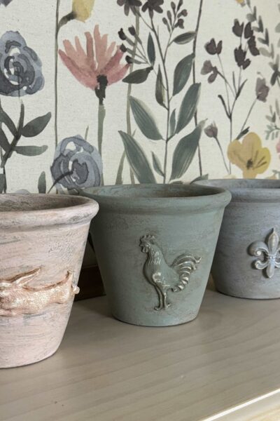 DIY flower pots embellished with air-dry clay and painted pastel colors.