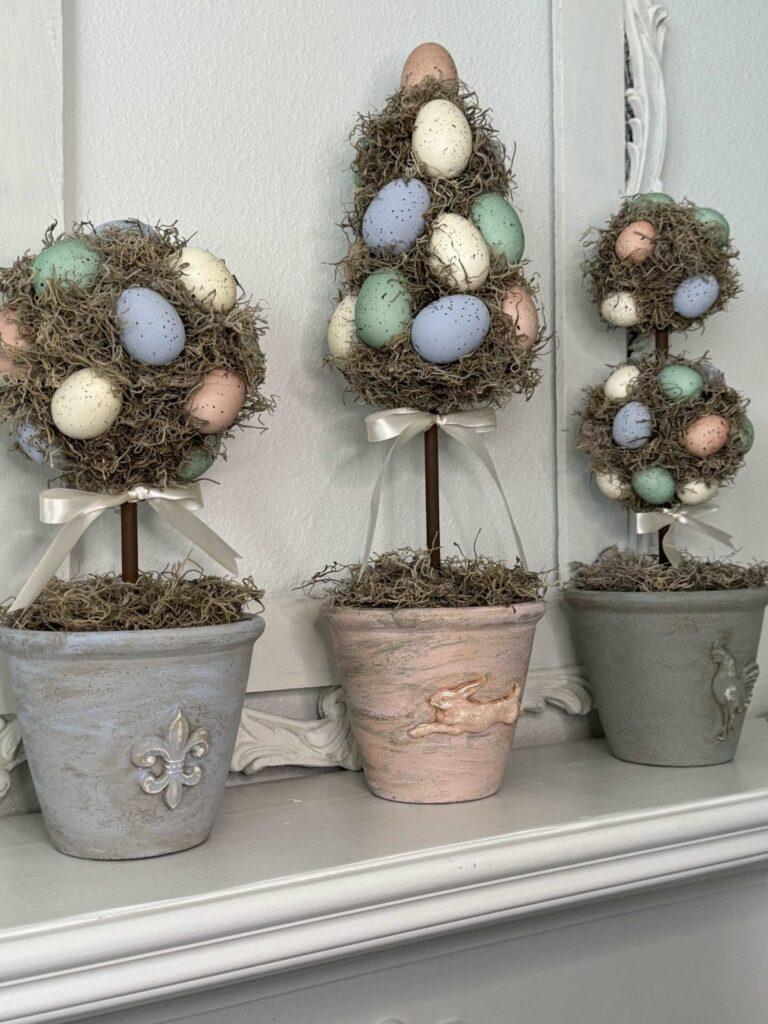 Three Easter egg topiaries on a mantel.