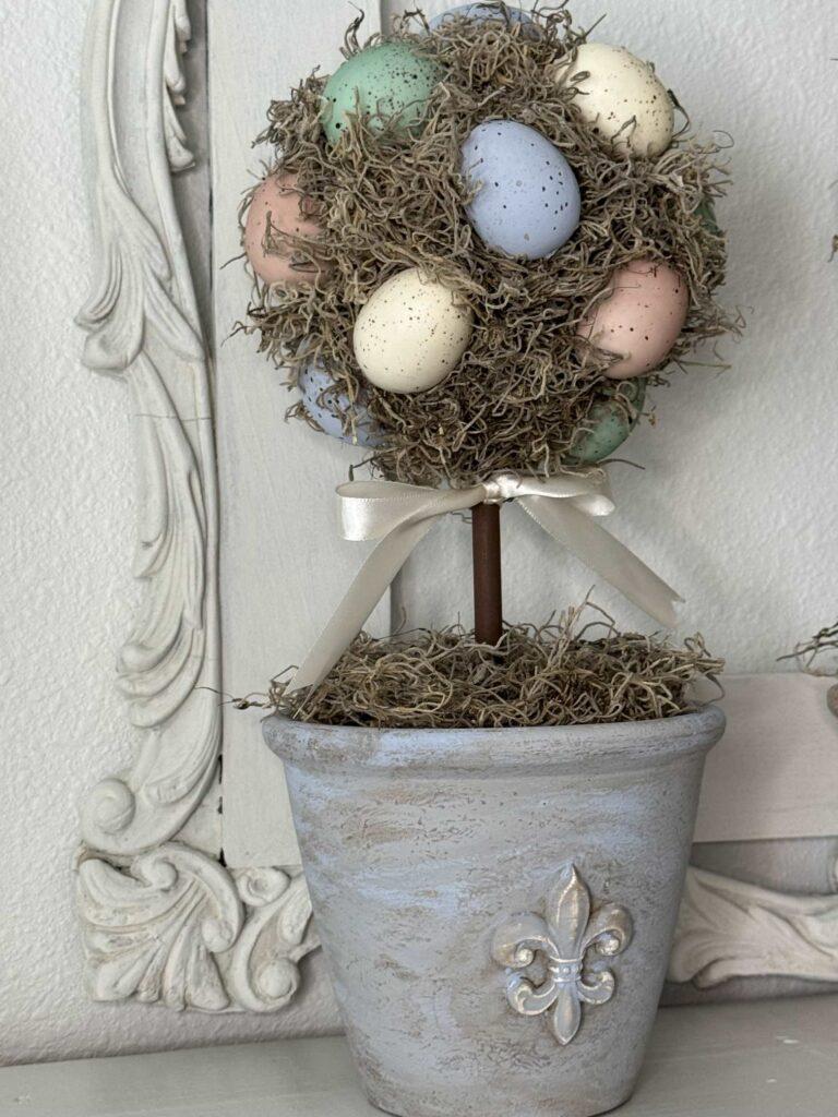 An Easter egg topiary in a blue fleur de lis pot. 