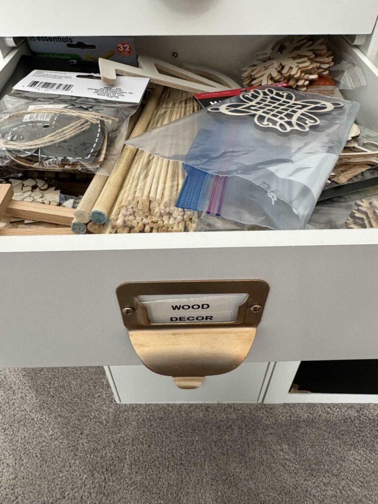 A disorganized drawer filled with wood craft items. 