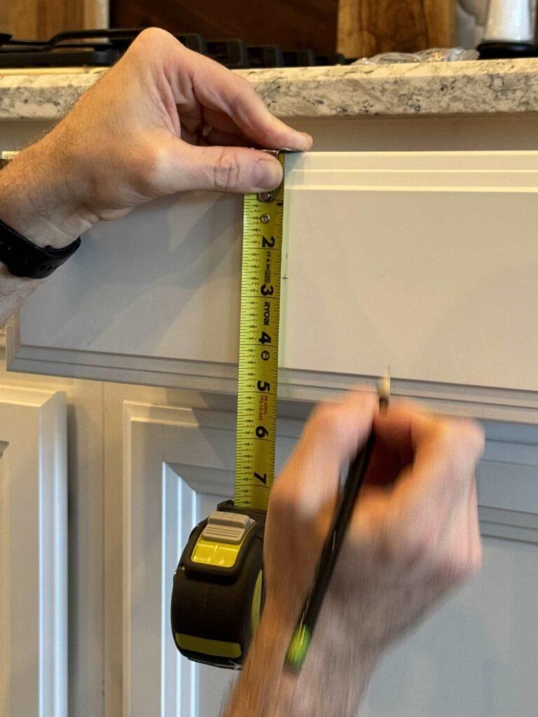 A person using a measuring tape to measure the height of a drawer. 