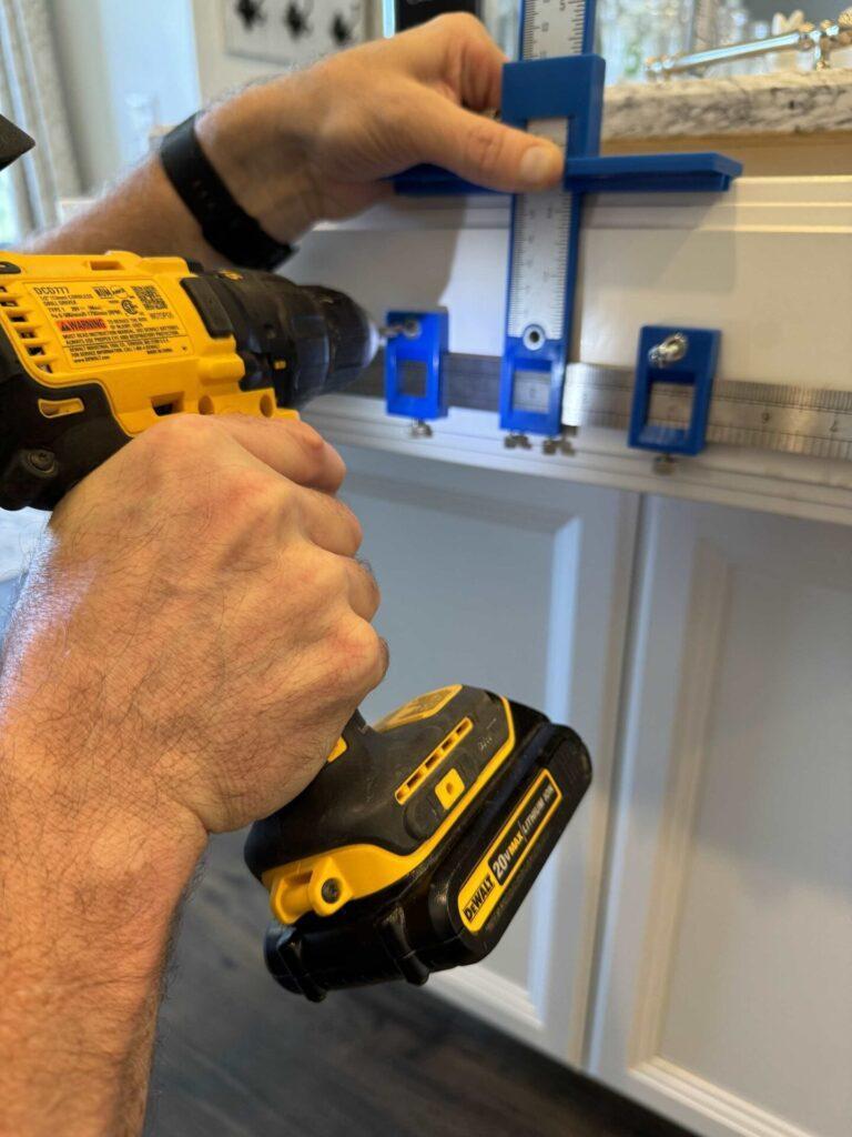 Someone drilling a hole through a jig into a drawer. 
