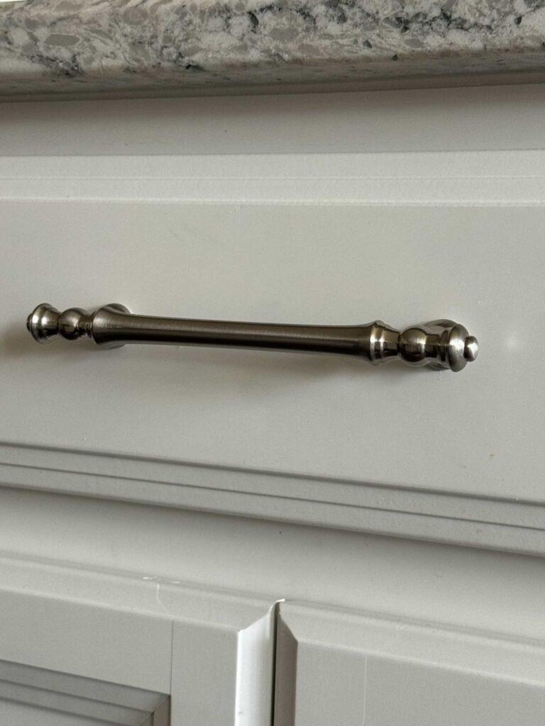 Silver handle on a white drawer. 
